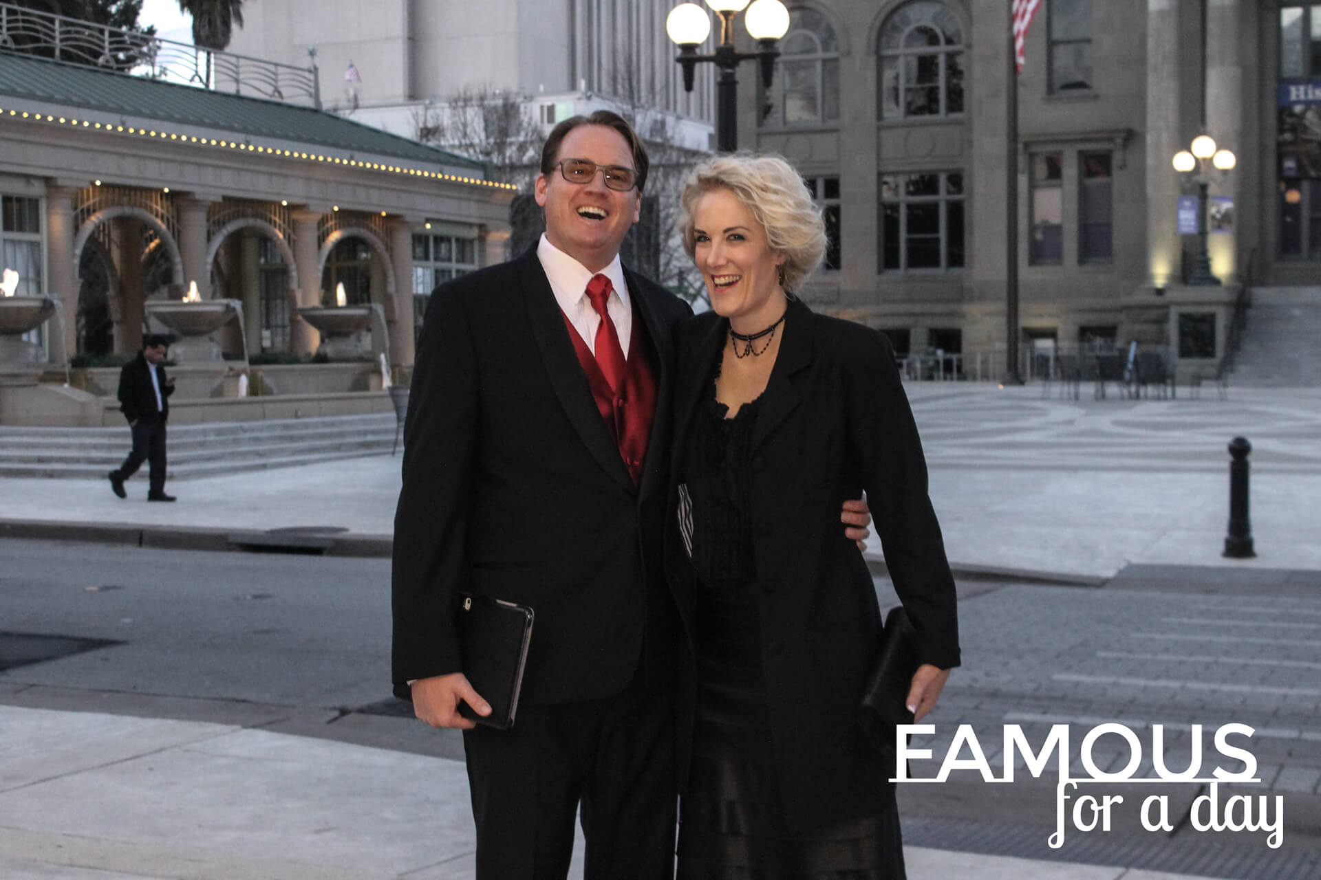 Couple dressed formally walking together under theater lights at night